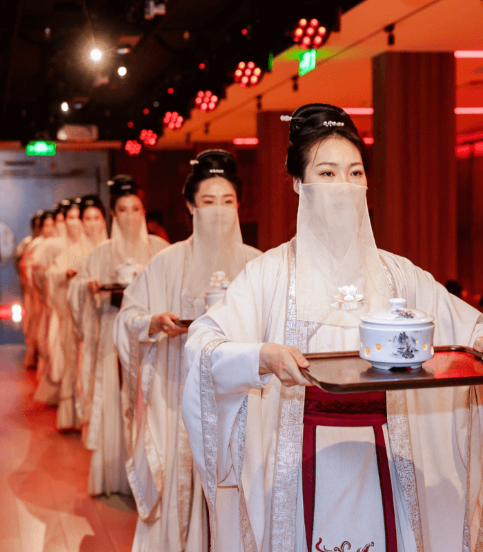 Traditional Chinese banquet hostesses in traditional attire carrying a course meal